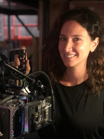 Woman smiling next to professional film camera.