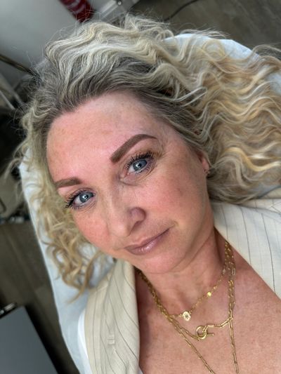 Close-up of a woman with curly blonde hair and blue eyes.