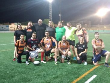 A group of rugby players posing on a lit field at night.