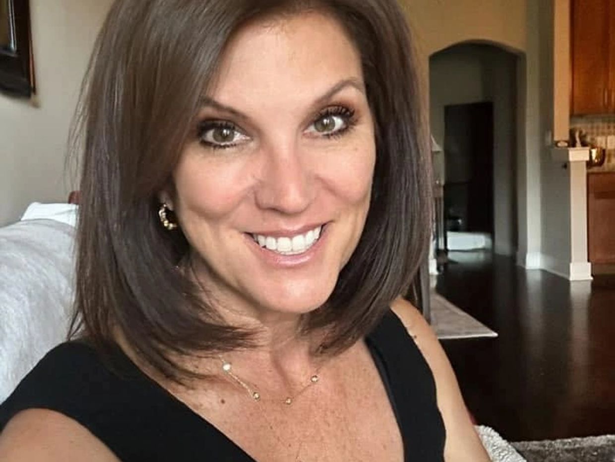 Woman smiling in a cozy indoor setting.