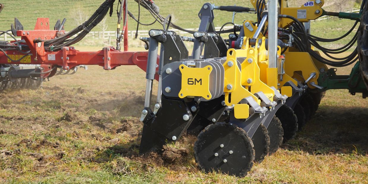 Close-up of agricultural machinery tilling soil in a field.
