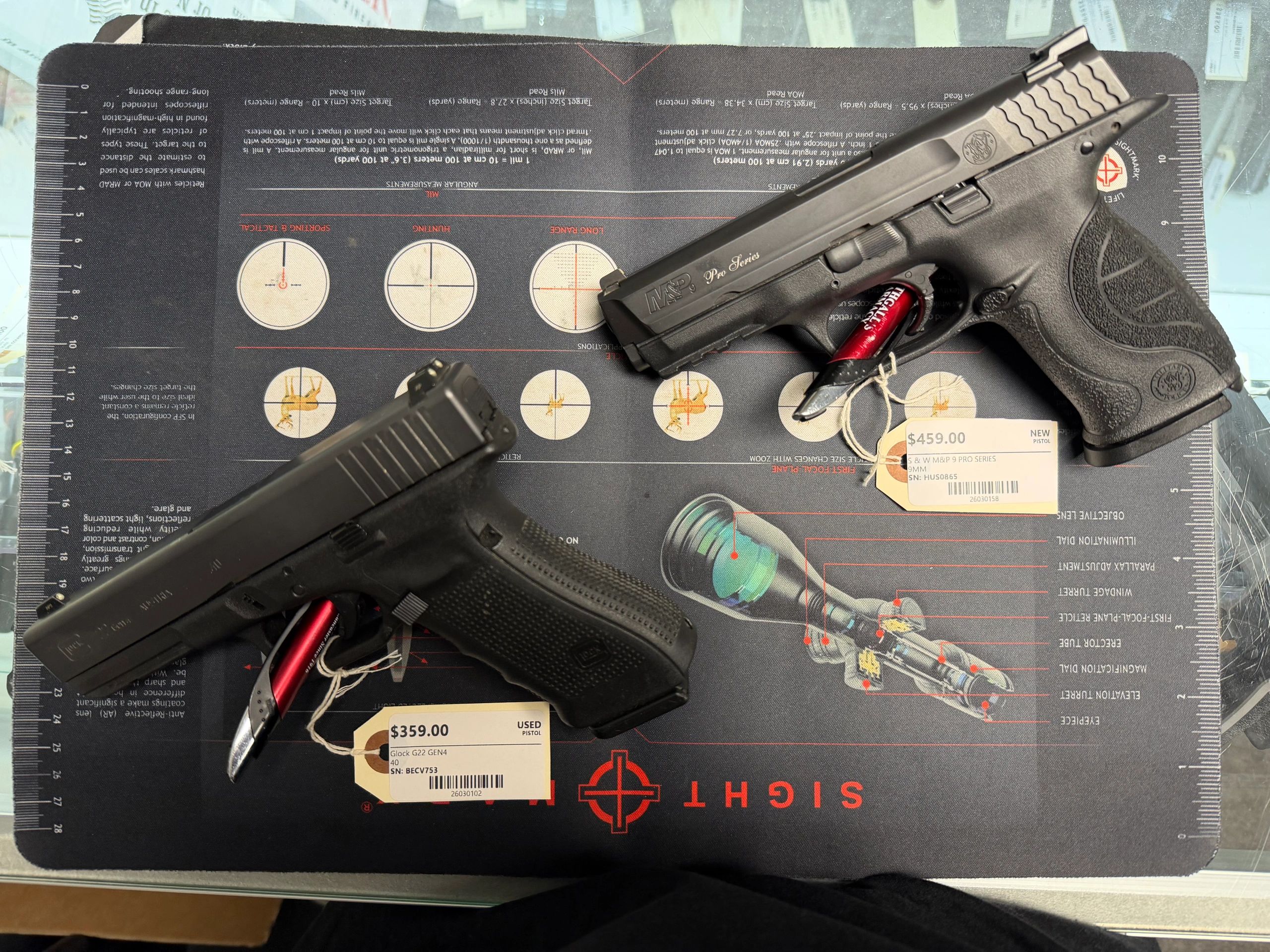 Two handguns with price tags displayed on a gun cleaning mat.