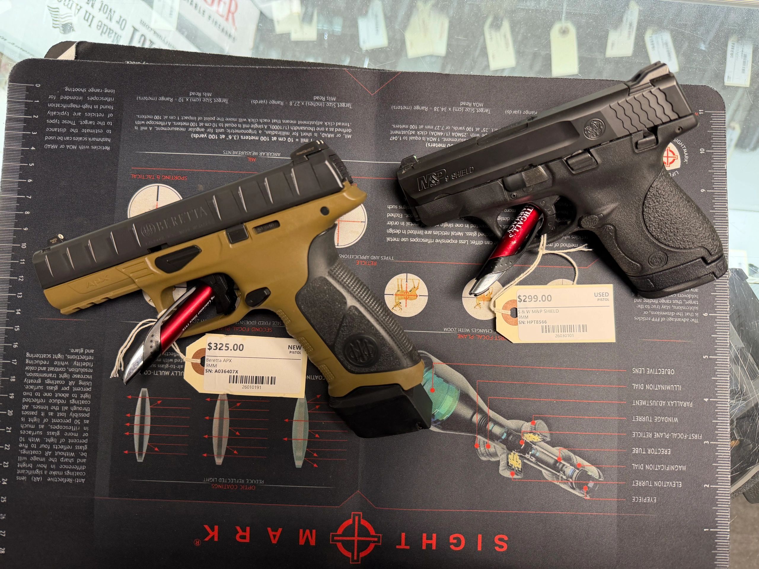 Two handguns displayed with price tags on a shooting mat.