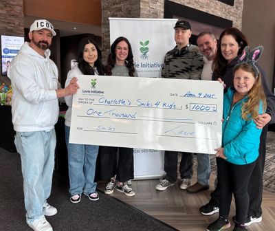 Group holding a large check for $1000 donation to Charlotte's Smiles 4 Kids.