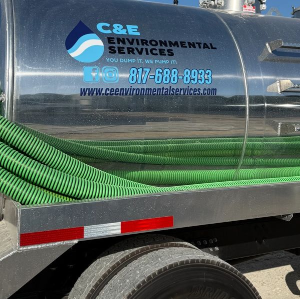 A close-up of a silver tank truck with green hoses displaying C&E Environmental Services logo and co