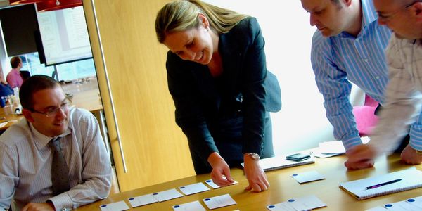 Team collaborating over cards on a table in a meeting.