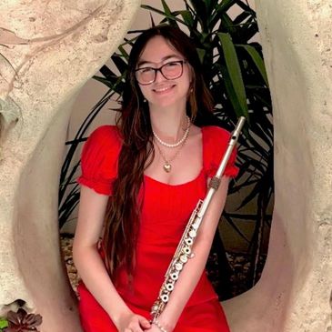 Young woman in a red dress holding a flute and smiling.