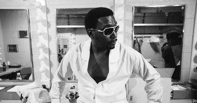 Man in sunglasses and open shirt posing confidently in a dressing room.