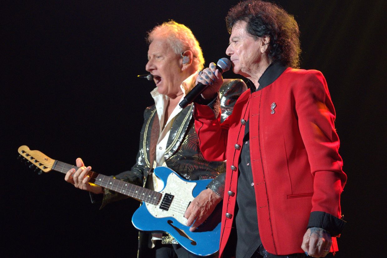Two male musicians performing on stage with guitar and microphone.