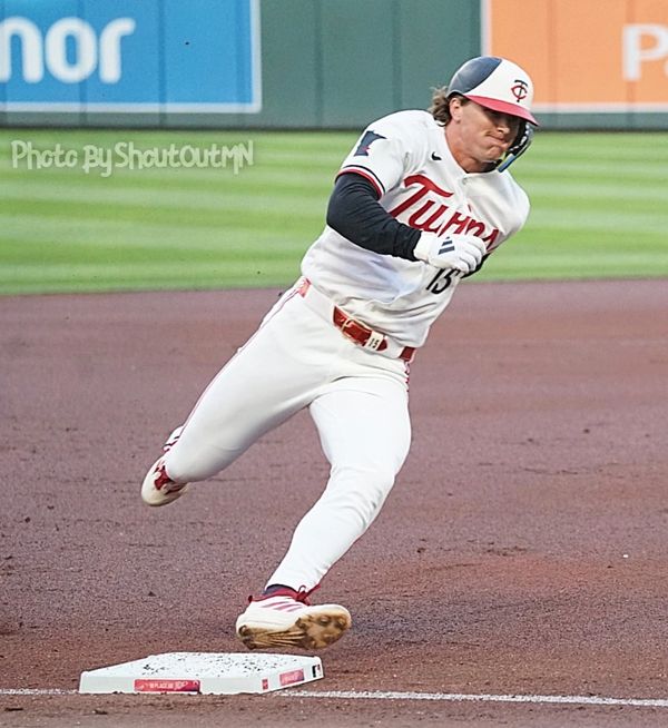 Baseball player from the Twins sliding into a base during a game.