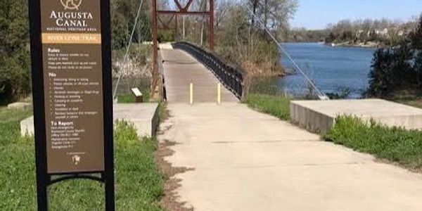 Entrance to Augusta Canal River Levee Trail with sign and bridge.