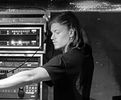 Woman adjusting audio equipment in a recording studio.