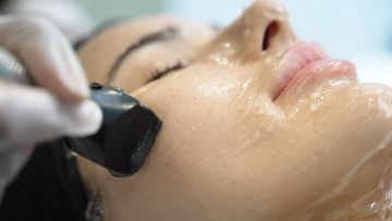 Close-up of a facial treatment with a skincare device.