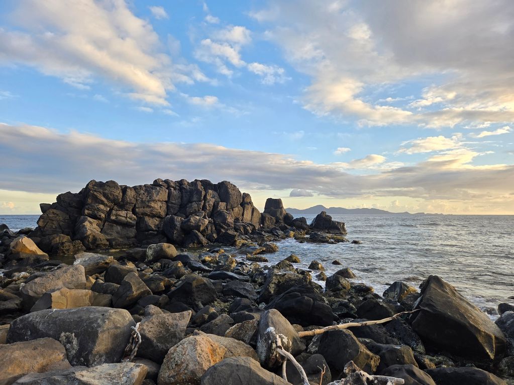 Canash Beach featuring rocks and driftwood in Saint Vincent with Bequia in view on the horizon