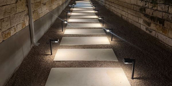 Lit pathway with rectangular stone slabs and small lights.