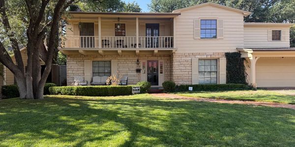 Two-story house with balcony and well-kept front yard.