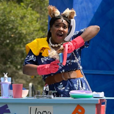 Iyana Colby as Mama Llama doing dishes while on the phone