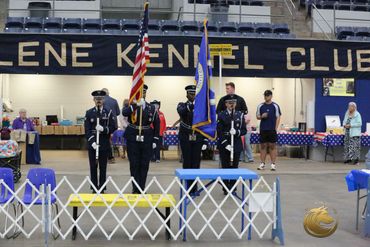 Color guard presenting flags at an indoor kennel club event.