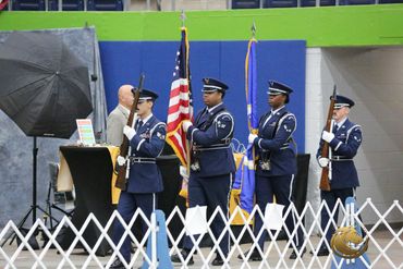 Honor guard presenting flags indoors at an event.