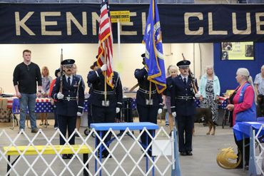 Color guard ceremony at a Kennel Club event with people observing.