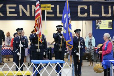 Honor guard presenting flags at a kennel club event.
