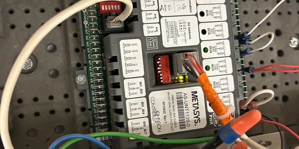 Close-up of a METASYS AS-UNT1126-01 electrical control module with connected wires.