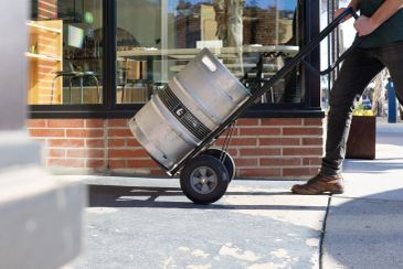 Person transporting a beer keg on a hand truck.