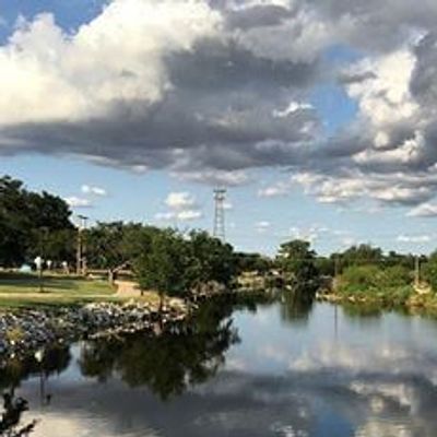 Calm river reflecting cloudy sky with ducks swimming.