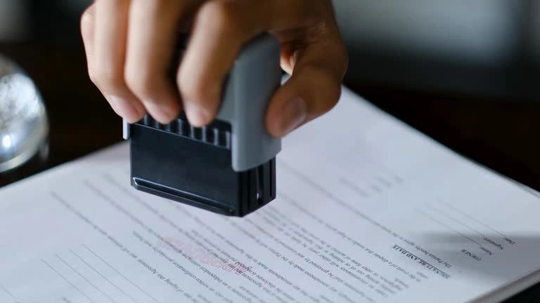 A hand stamping a document with a stamp.