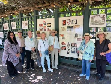 Group of women posing under a pergola with display boards.