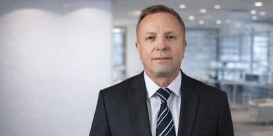 Professional man in suit posing in modern office space.