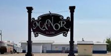 A black sign reading 'Manor' with buildings in the background.