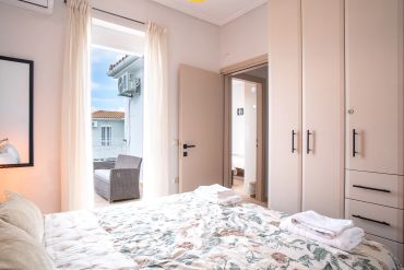 Cozy bedroom with floral bedding and balcony access featuring wicker furniture.