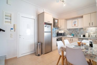 Bright modern kitchen with beige cabinets and a dining table set for breakfast.