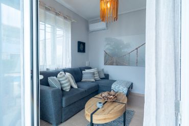 Cozy living room with blue sofa, wooden coffee table, and soft natural light.