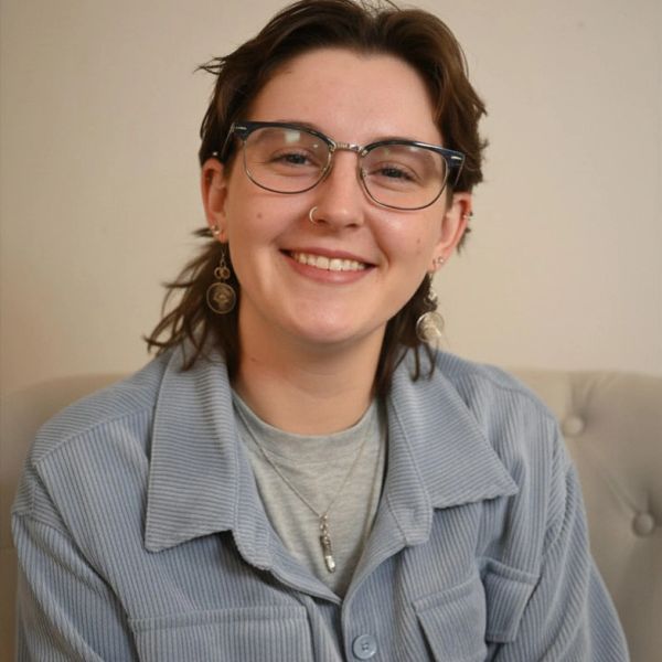 Smiling person with glasses and earrings.