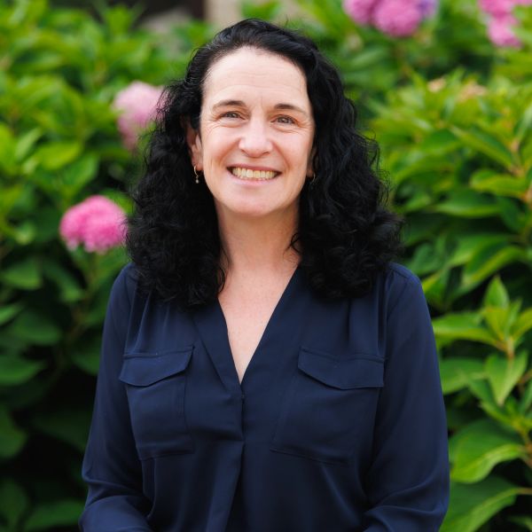 Woman with curly dark hair smiling outdoors.