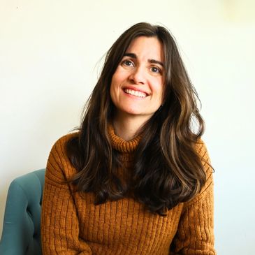 Smiling woman with long brown hair wearing a brown sweater.