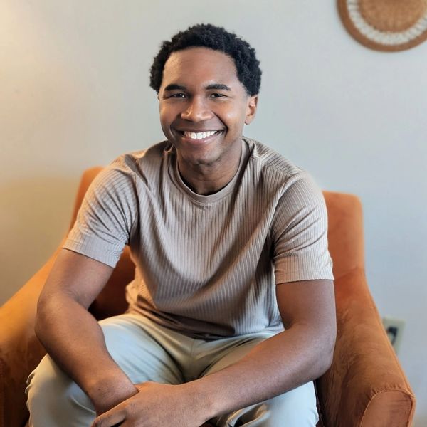 Smiling man sitting on an orange armchair indoors.