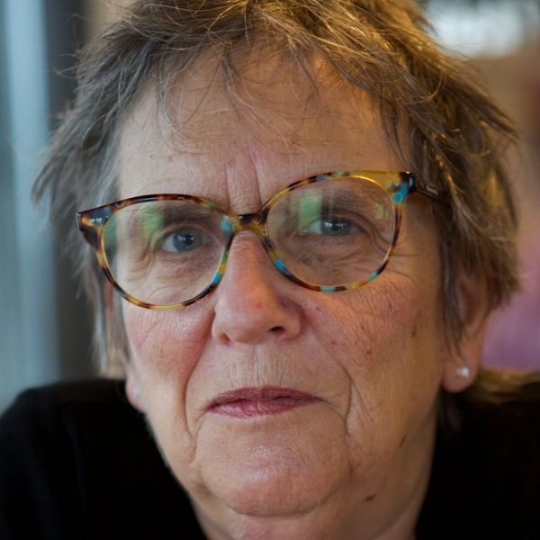 Close-up of an elderly woman with patterned glasses and short hair.
