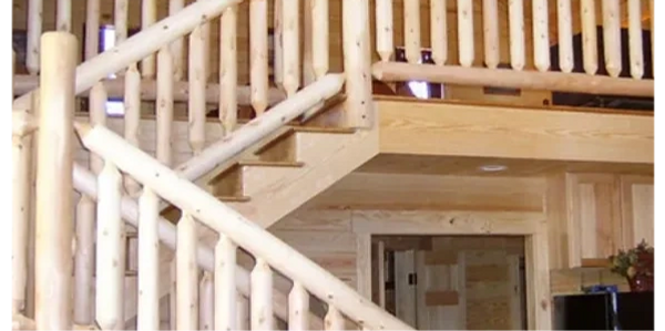 Wooden staircase and railing inside a log cabin interior.