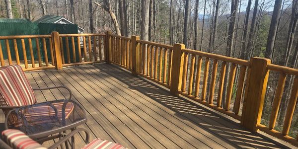 Wooden deck with striped chairs overlooking a forest.