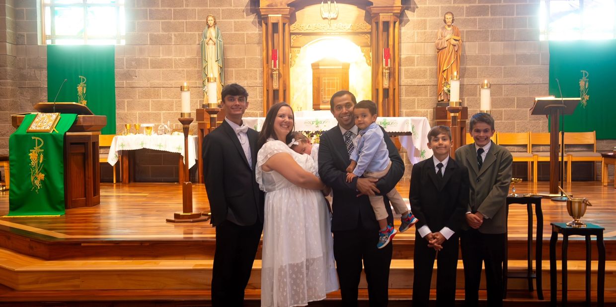 A family dressed formally posing in a church near the altar.