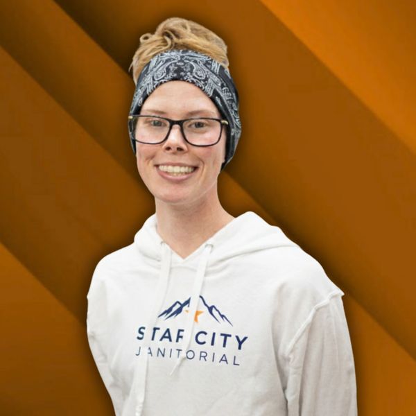 Smiling person in a white Star City Janitorial hoodie and patterned headband.