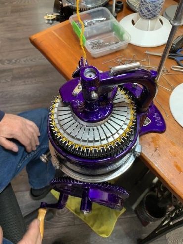 Vintage purple circular knitting machine in use.