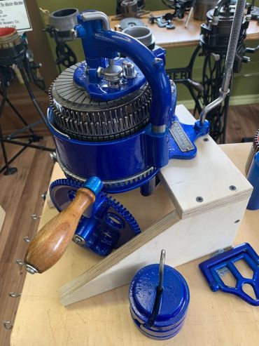 Vintage blue knitting machine with wooden handle.
