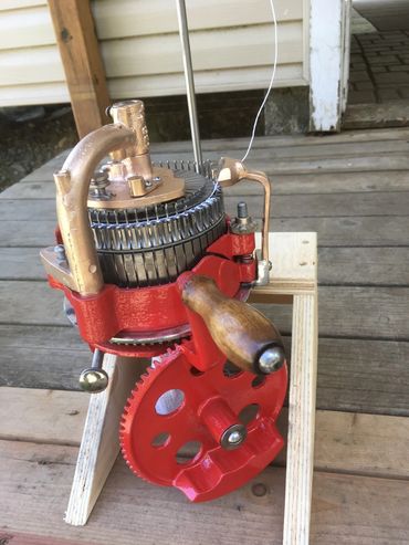Vintage red hand-crank knitting machine with wooden handle.