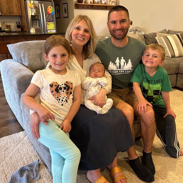 A happy family of five posing on a couch in their living room.
