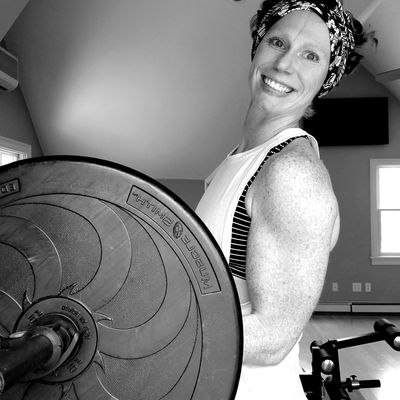Smiling woman lifting weights in a gym.