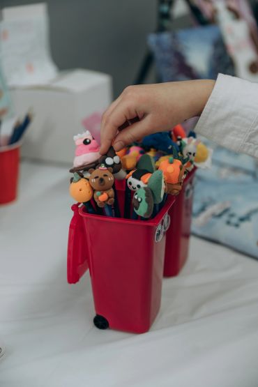 Hand picking a colorful decorated pencil from a red container.